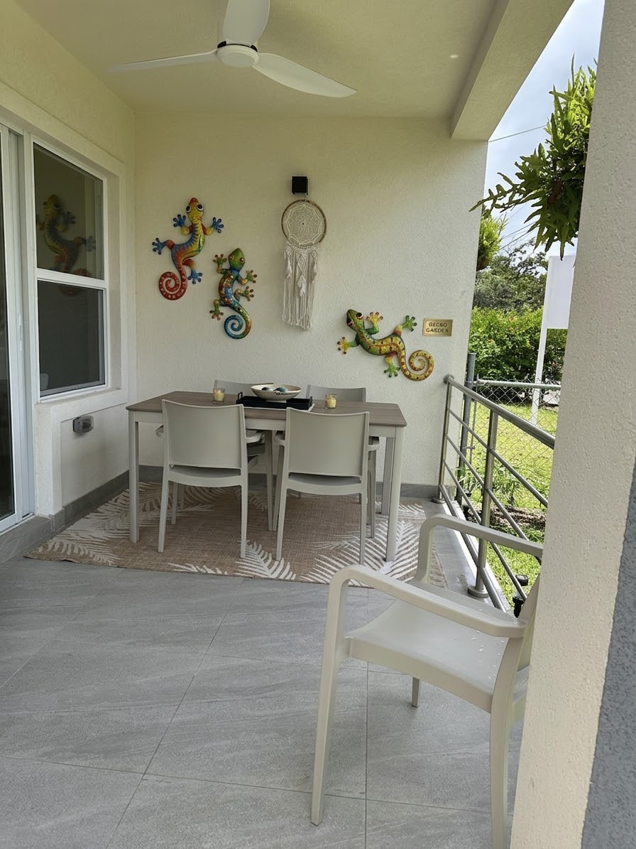 The covered patio with a dining table and chairs beside the garden wall.